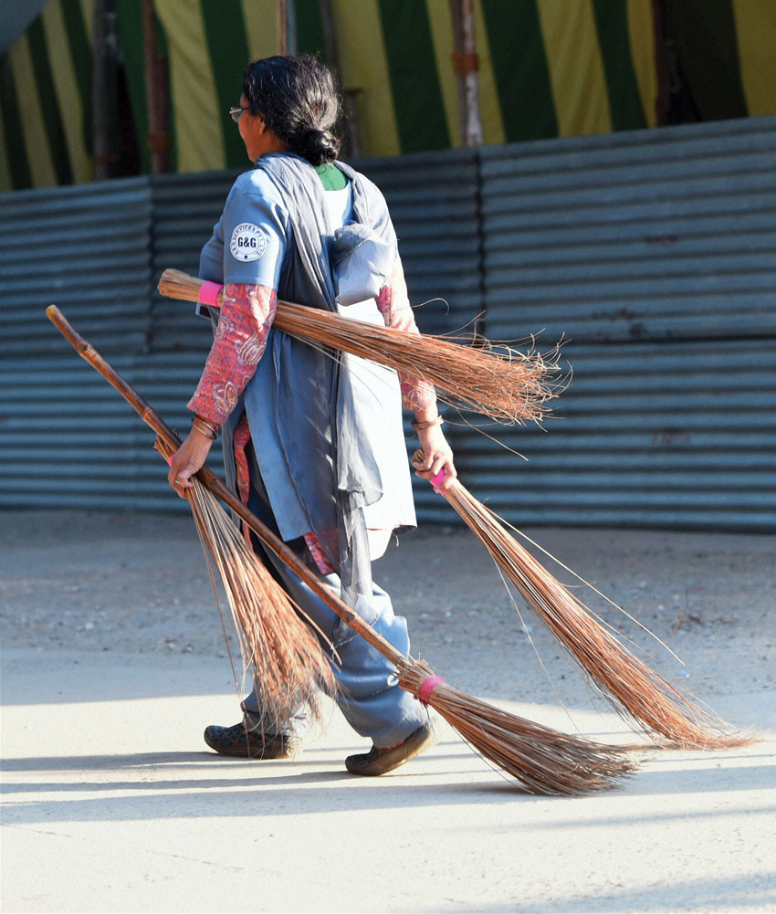 A woman carrying brooms at a poll counting center in New Delhi, Feb. 10. (Shahbaz Khan | PTI)