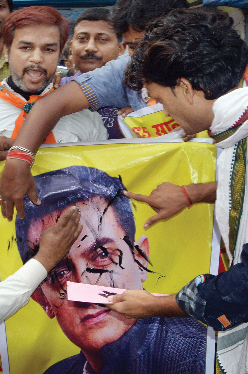 BJP workers smearing black ink on a poster of Aamir Khan in Patna, Nov. 24. (Press Trust of India)