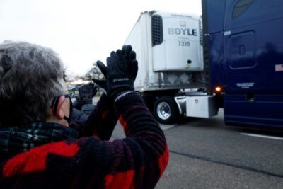 Susan Deur cheers as trucks carrying the first shipment of the Covid-19 vaccine, escorted by the US Marshals Service, leave Pfizer's Global Supply facility in Kalamazoo, Michigan. ©AFP JEFF KOWALSKY